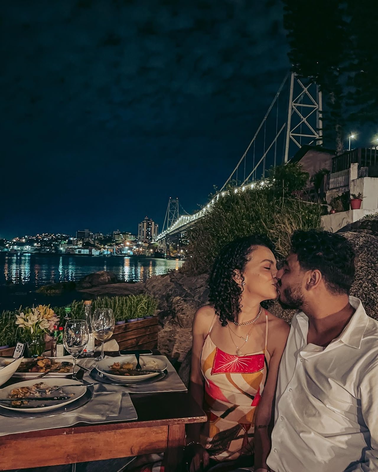 Cássia e Pablo se beijando em jantar à beira da ponte